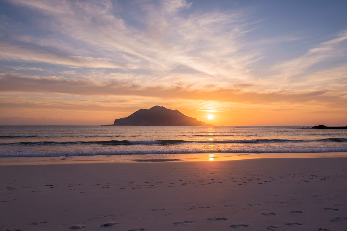 The sun setting beside Biyangdo's silhouette as long shadows stretch across Geumneung's sand