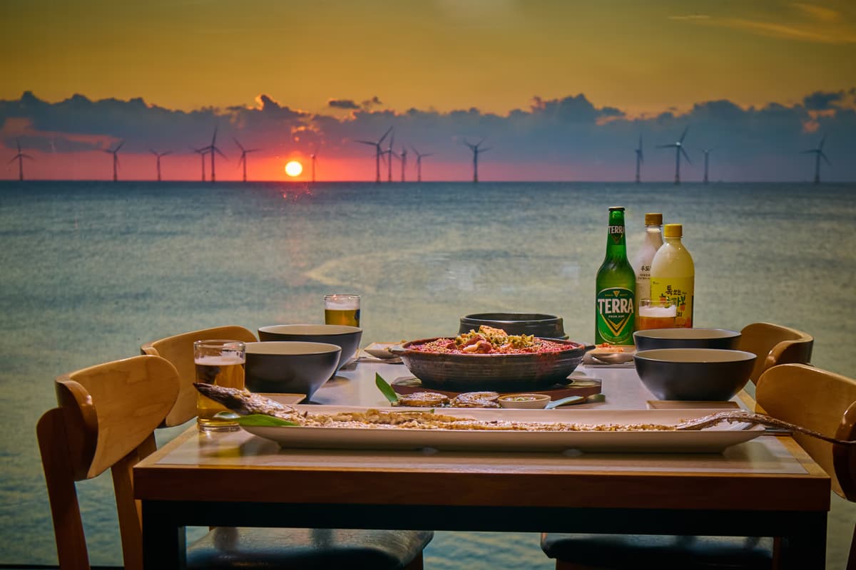Galchibada Aewol Terra beer and Hallabong makgeolli with a wind-turbine sunset ocean view